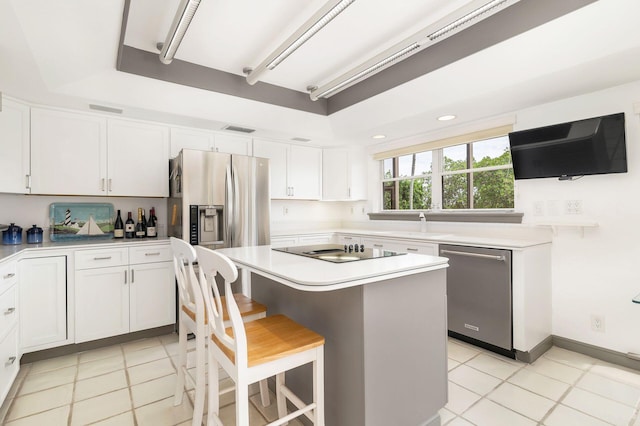 kitchen featuring white cabinets, a breakfast bar, stainless steel appliances, and a kitchen island