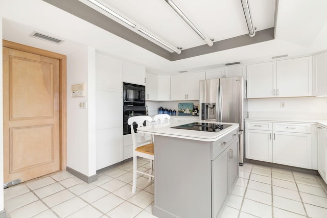 kitchen featuring white cabinets, a kitchen breakfast bar, a kitchen island, and black appliances