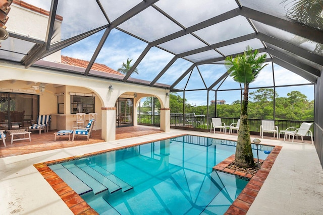 view of pool with glass enclosure, ceiling fan, and a patio