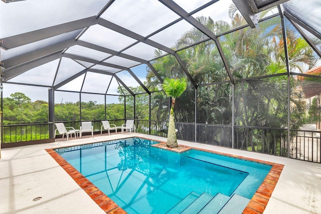 view of swimming pool featuring glass enclosure and a patio