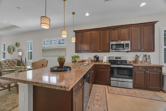 kitchen featuring decorative light fixtures, sink, light stone countertops, dark brown cabinetry, and appliances with stainless steel finishes