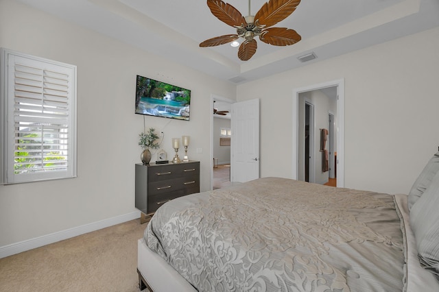 carpeted bedroom featuring ceiling fan and a tray ceiling