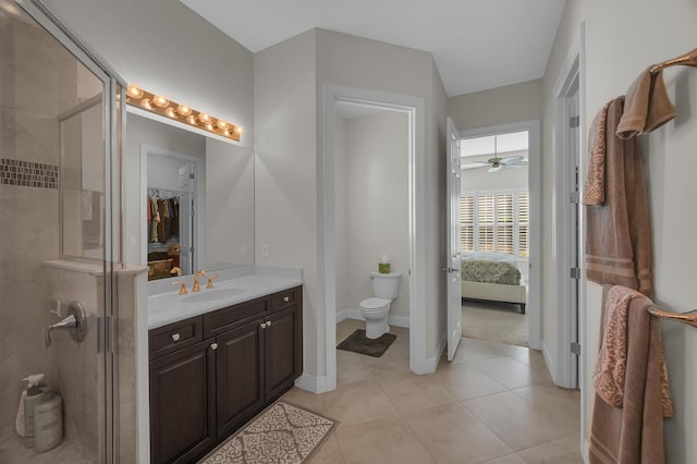 bathroom with tile patterned flooring, a shower with shower door, toilet, vanity, and ceiling fan