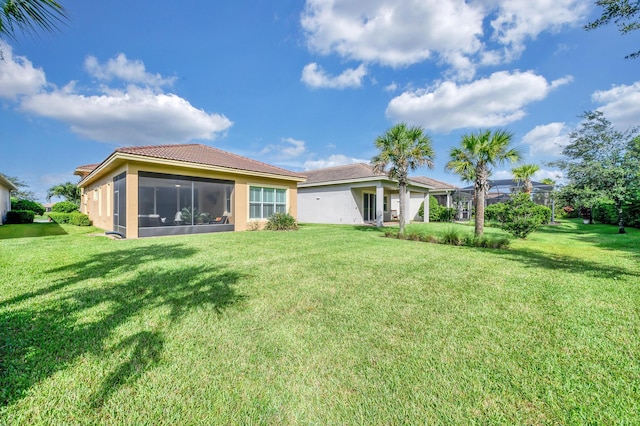 rear view of house with a sunroom and a lawn