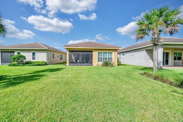 rear view of property featuring a yard and a sunroom