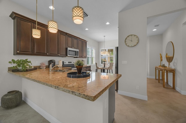 kitchen featuring appliances with stainless steel finishes, decorative light fixtures, kitchen peninsula, and dark brown cabinetry