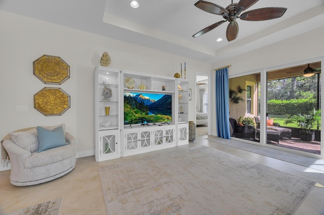 tiled living room featuring ceiling fan and a tray ceiling