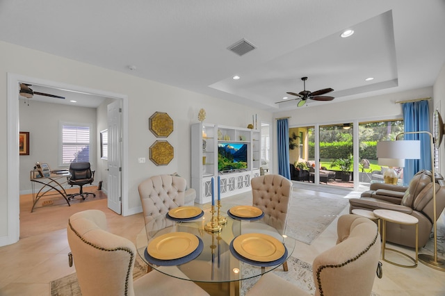 living room with light tile patterned floors, ceiling fan, and a tray ceiling