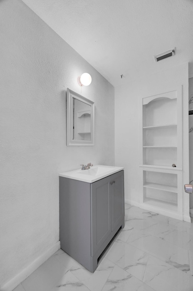 bathroom with vanity, built in features, and a textured ceiling