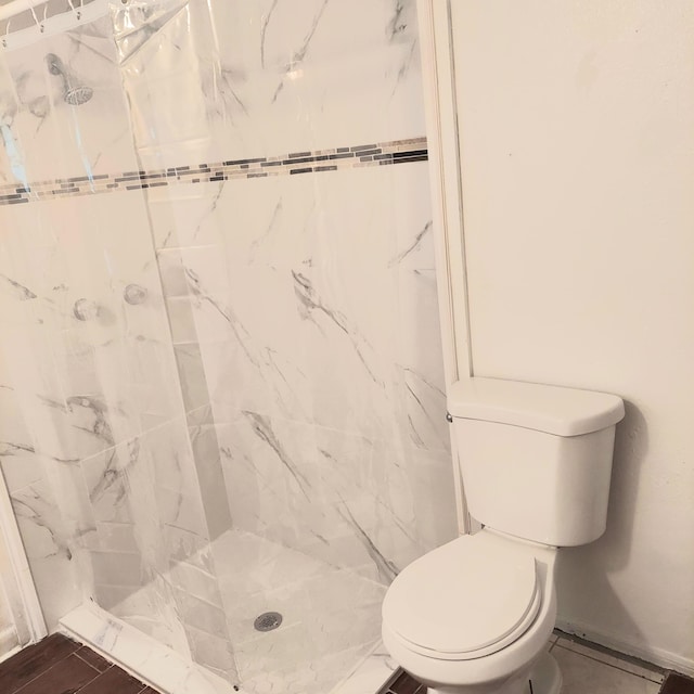 bathroom with a tile shower and toilet