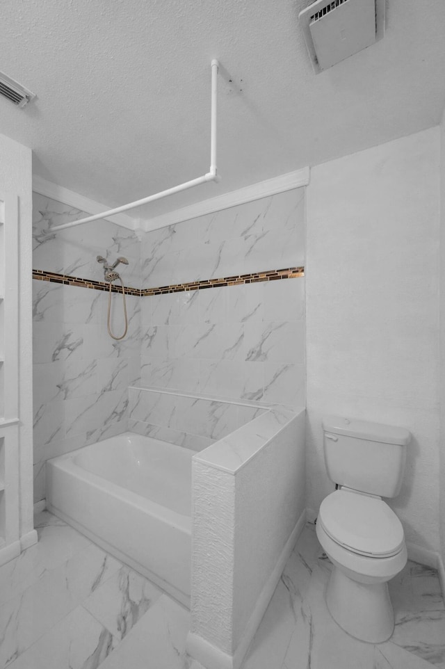 bathroom featuring toilet, tiled shower / bath, and a textured ceiling