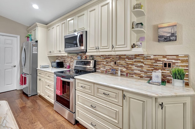 kitchen with dark wood-type flooring, tasteful backsplash, stainless steel appliances, and light stone counters