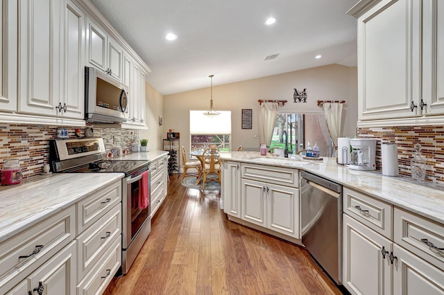 kitchen featuring light hardwood / wood-style flooring, tasteful backsplash, vaulted ceiling, and stainless steel appliances