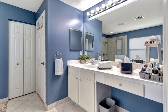 bathroom with vanity, tile patterned flooring, and tiled shower