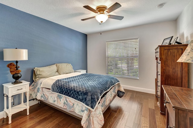 bedroom featuring hardwood / wood-style flooring, a textured ceiling, and ceiling fan