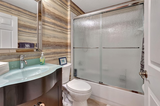 full bathroom featuring vanity, tile patterned floors, shower / bath combination with glass door, toilet, and a textured ceiling