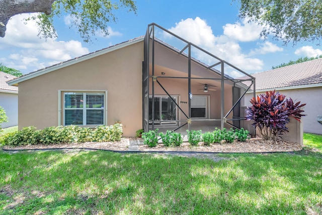 back of property with ceiling fan and a lawn