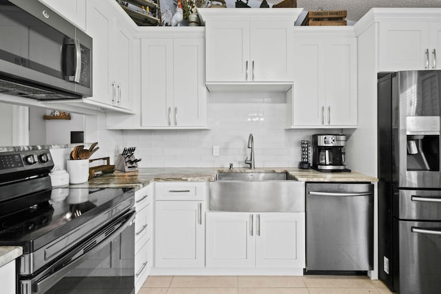 kitchen featuring tasteful backsplash, light tile patterned floors, stainless steel appliances, and white cabinetry