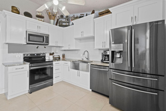 kitchen featuring ceiling fan, appliances with stainless steel finishes, light tile patterned floors, and backsplash