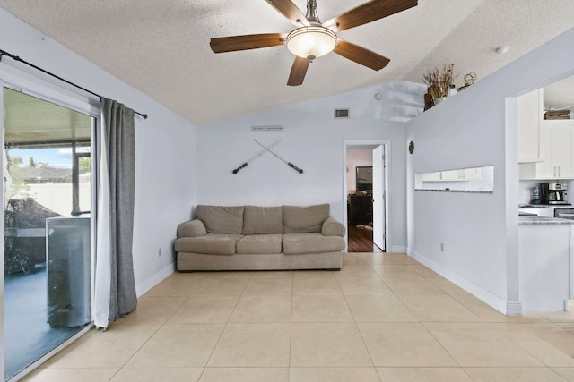 tiled living room featuring ceiling fan, vaulted ceiling, and a textured ceiling