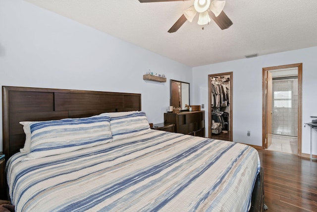 bedroom featuring a textured ceiling, ceiling fan, a spacious closet, dark hardwood / wood-style flooring, and a closet