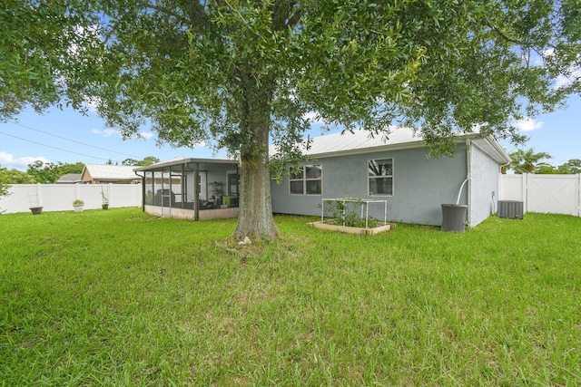 rear view of property with a lawn, a sunroom, and central AC unit