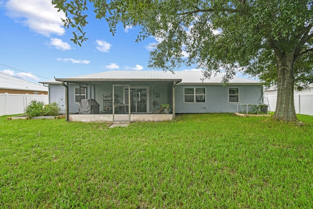 back of property with a sunroom and a lawn