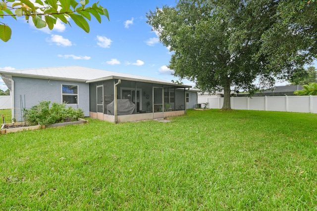 back of house featuring a sunroom and a lawn