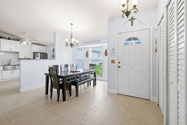 dining area with light tile patterned floors, sink, ceiling fan with notable chandelier, and a textured ceiling