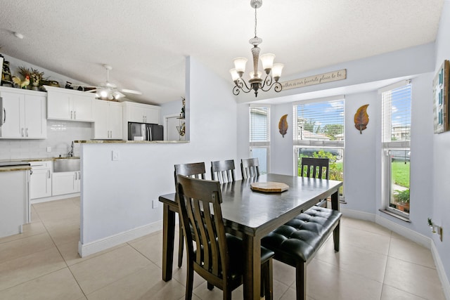 tiled dining space featuring ceiling fan with notable chandelier, a textured ceiling, and lofted ceiling