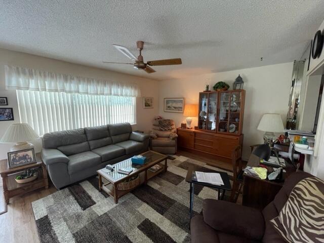 living room featuring ceiling fan, hardwood / wood-style flooring, and a textured ceiling