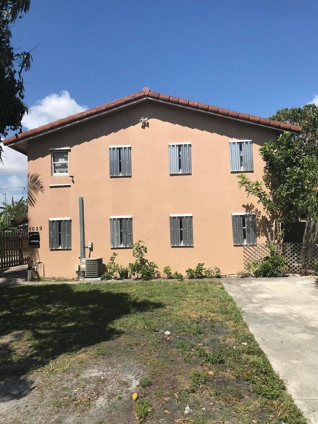 view of side of property with central AC and a lawn