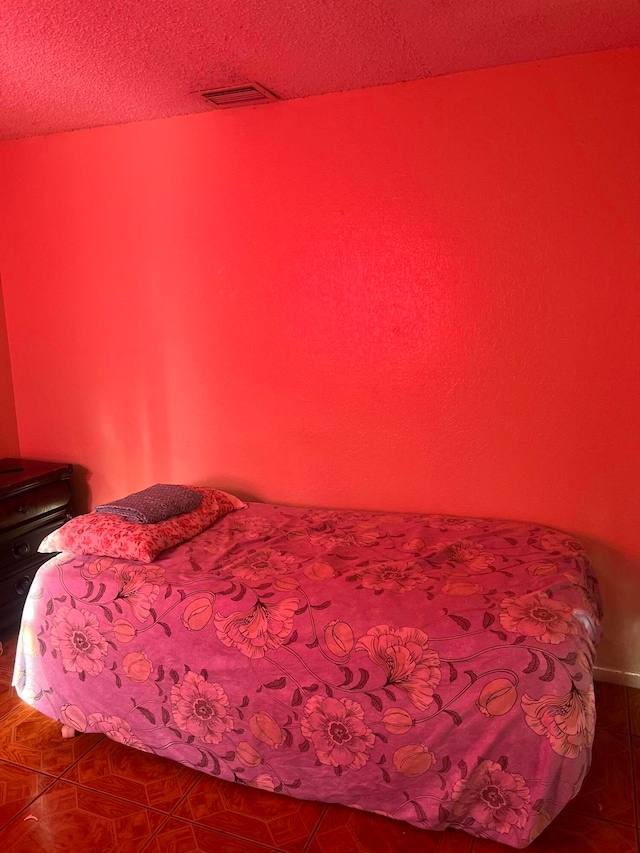 bedroom with a textured ceiling and tile patterned flooring