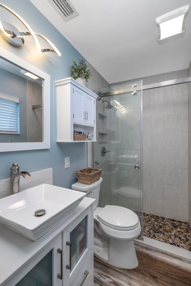 bathroom with a shower with shower door, wood-type flooring, vanity, and toilet