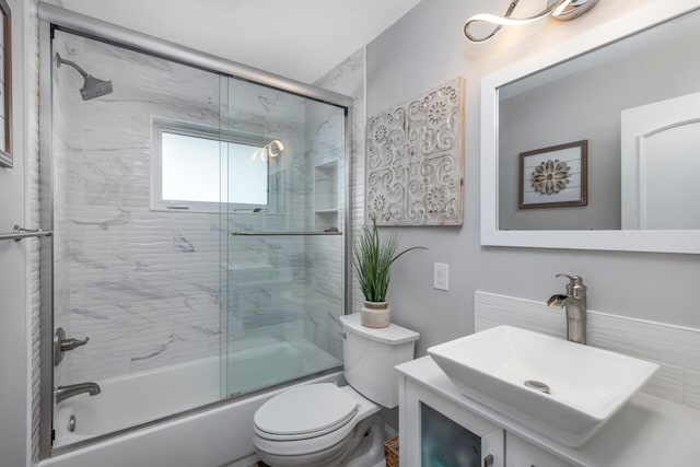 full bathroom featuring toilet, bath / shower combo with glass door, and vanity