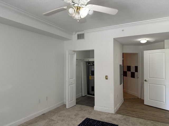 unfurnished bedroom with crown molding, a textured ceiling, ceiling fan, electric water heater, and light colored carpet