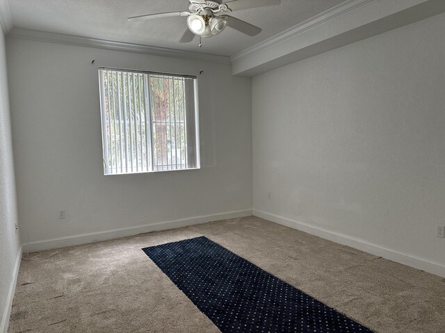 carpeted spare room with a textured ceiling, ornamental molding, and ceiling fan