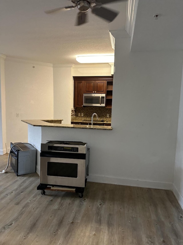 kitchen with stainless steel appliances, ornamental molding, wood-type flooring, and sink