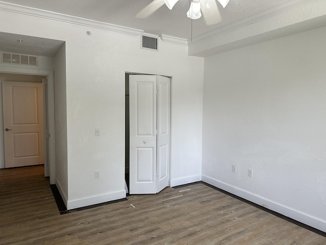 unfurnished bedroom featuring crown molding, ceiling fan, hardwood / wood-style floors, and a closet