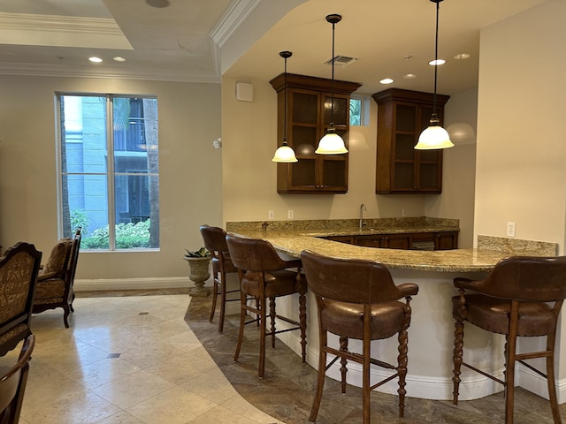 bar featuring sink, crown molding, stone counters, a tray ceiling, and decorative light fixtures