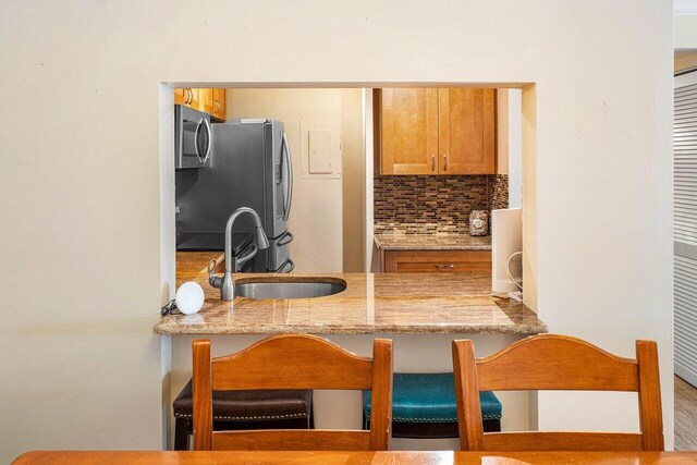 kitchen with sink, decorative backsplash, appliances with stainless steel finishes, and light stone countertops