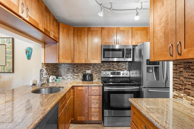 kitchen featuring stainless steel appliances, rail lighting, sink, and a textured ceiling