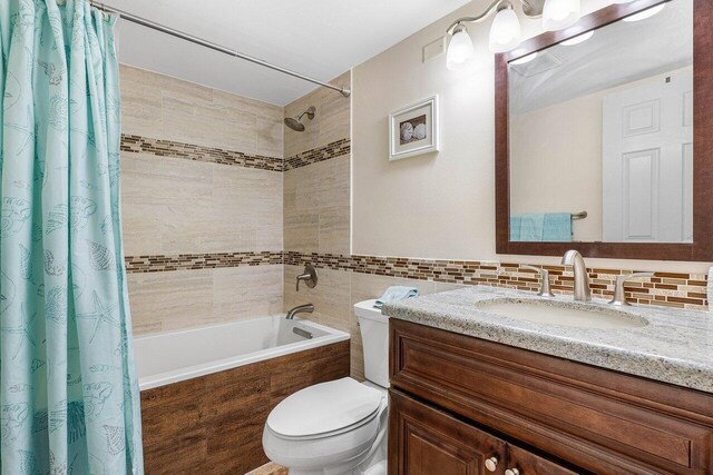 full bathroom featuring shower / tub combo, tile walls, decorative backsplash, toilet, and vanity