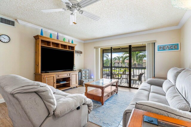 living room with light hardwood / wood-style floors, a textured ceiling, ornamental molding, and ceiling fan