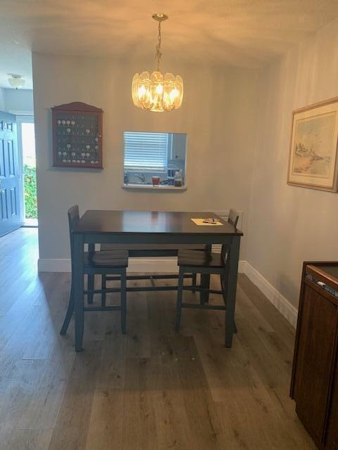 dining space with an inviting chandelier, baseboards, and wood finished floors