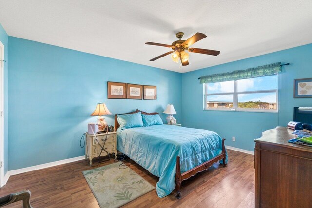 bedroom with ceiling fan, dark wood finished floors, and baseboards