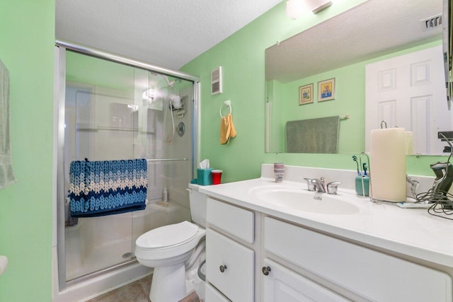 bathroom with vanity, tile patterned floors, toilet, a shower with door, and a textured ceiling