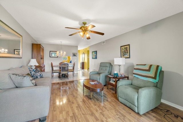 living room featuring ceiling fan with notable chandelier, light wood-type flooring, visible vents, and baseboards