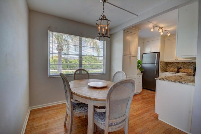 dining room with baseboards, an inviting chandelier, and light wood finished floors