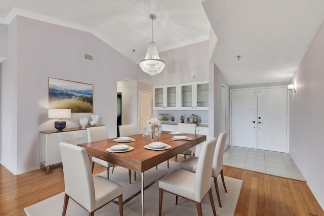 dining area featuring light hardwood / wood-style floors, vaulted ceiling, and a notable chandelier